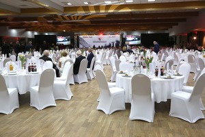 Zdjęcie przedstawia salę pełną białych stolików i krzeseł. (photo)