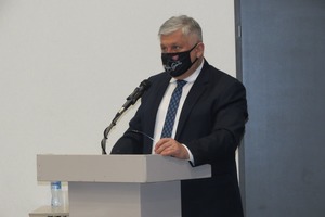 Na zdjęciu znajduje się Burmistrz Karol Skrzypczak. Mężczyzna przemawia do mikrofonu na mównicy. Ma ubraną czarną maseczkę, zasłaniającą usta i nos.  (photo)
