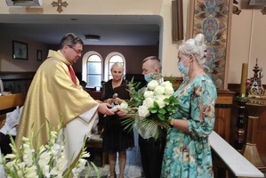 Na zdjęciu znajduje się ksiądz odbierający bukiet kwiatów od parafian. (photo)