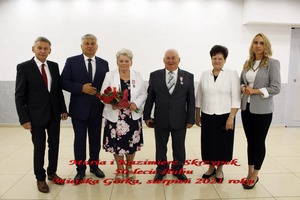 Na zdjęciu znajdują się trzej mężczyźni w garniturach oraz trzy kobiety, jedna z nich trzyma w ręce kwiaty.  (photo)