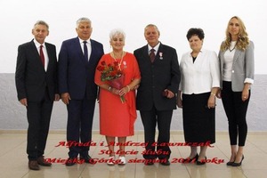 Na zdjęciu znajdują się trzej mężczyźni w garniturach oraz trzy kobiety, jedna z nich trzyma w ręce kwiaty.  (photo)
