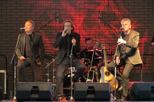 Na scenie znajdują się trzej siedzący i śpiewający mężczyźni. Występ zespołu VOX (photo)