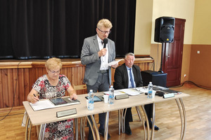 Przewodniczący Rady Miejskiej przemawiający na stojąco. Po jego obu stronach zasiadają wiceprzewodniczący Rady (photo)