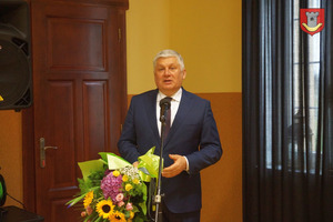 Burmistrz Miejskiej Górki przemawia podczas sesji, w rękach trzyma bukiet kwiatów (photo)